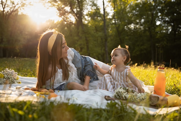 Una giovane mamma e la sua figlioletta fanno un picnic in un parco cittadino.