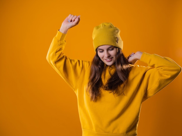 Una giovane mora allegra in abiti luminosi sta ballando e si diverte una giovane donna con un cappuccio giallo...