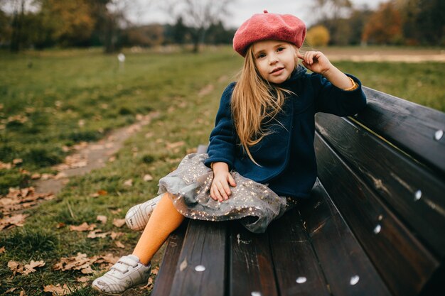 Una giovane ragazza alla moda in posa sulla panchina