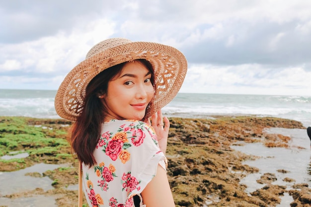 Una giovane ragazza asiatica che indossa un cappello da spiaggia si sta rilassando sulla spiaggia del cielo blu a Gunungkidul Indonesia