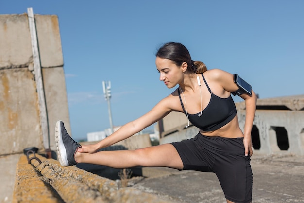 Una giovane ragazza atletica esile in abiti sportivi esegue una serie di esercizi Fitness e stile di vita sano