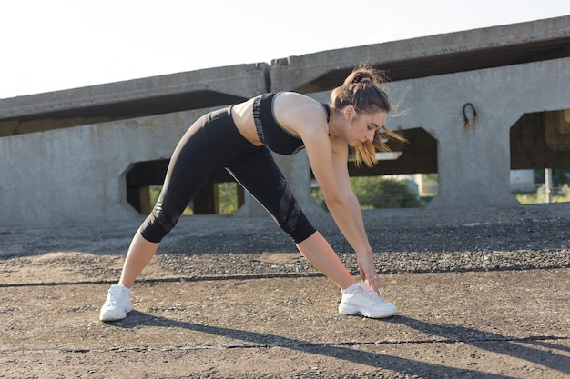 Una giovane ragazza atletica magra in abbigliamento sportivo esegue una serie di esercizi.