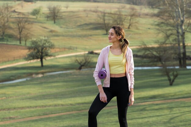 Una giovane ragazza atletica snella in abbigliamento sportivo esegue una serie di esercizi Fitness e stile di vita sano sullo sfondo delle verdi colline dei pascoli primaverili