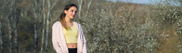 Una giovane ragazza atletica snella in abbigliamento sportivo esegue una serie di esercizi Fitness e stile di vita sano sullo sfondo delle verdi colline dei pascoli primaverili