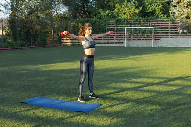 Una giovane ragazza atletica snella in abiti sportivi con stampe in pelle di serpente esegue una serie di esercizi