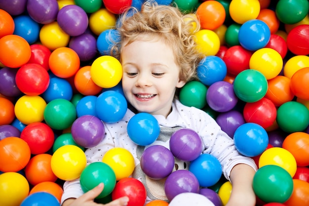 Una giovane ragazza bionda che si diverte a giocare con le palline di plastica? Olorful