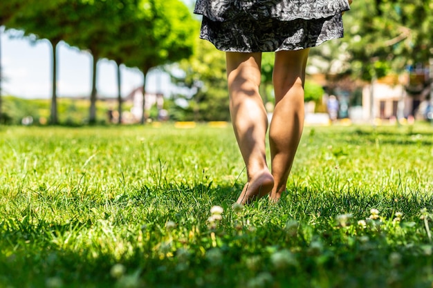 Una giovane ragazza cammina a piedi nudi su un prato verde Vista posteriore