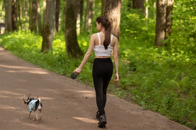 Una giovane ragazza cammina con un cagnolino nel parco