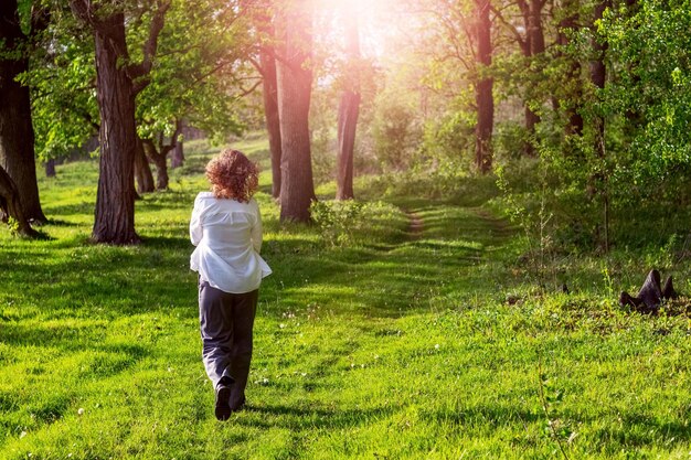 Una giovane ragazza cammina lungo una strada forestale vicino a un fiume in un clima estivo soleggiato Una passeggiata nella foresta