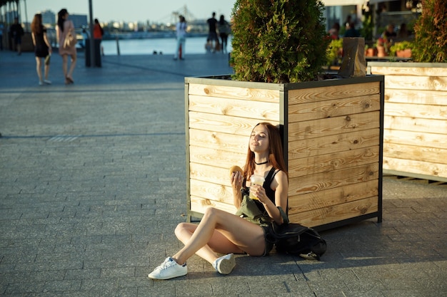 Una giovane ragazza cena fast food nella piazza del paese