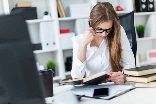 Una giovane ragazza che lavora in ufficio con libri e documenti.