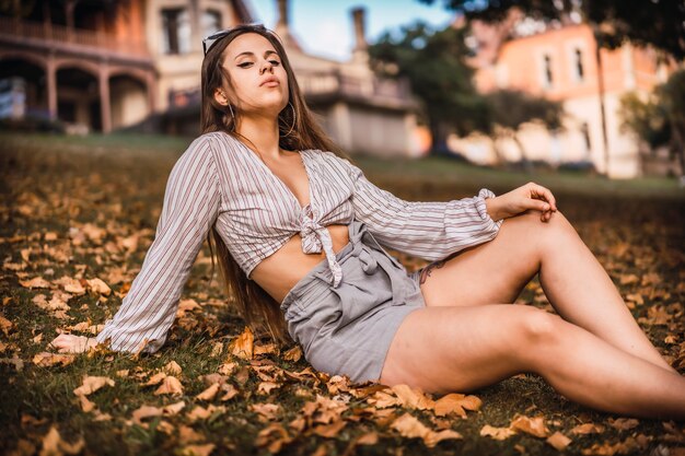 Una giovane ragazza con una camicia a righe in uno stile di vita seduto seduto con un edificio in background