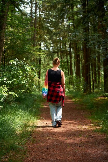 Una giovane ragazza con una flanella intorno alla vita che cammina attraverso un sentiero in una foresta