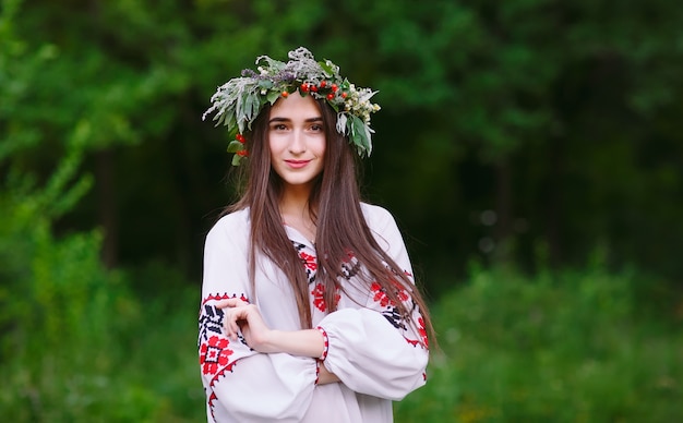 Una giovane ragazza di aspetto slavo con una ghirlanda di fiori selvatici a metà estate.