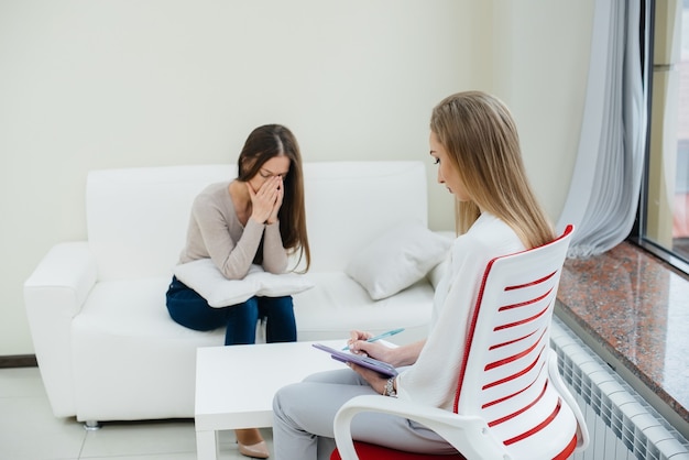 Una giovane ragazza durante la depressione comunica con uno psicologo in ufficio. Aiuto psicologico.