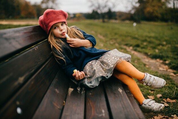 Una giovane ragazza glamour in posa sulla panchina