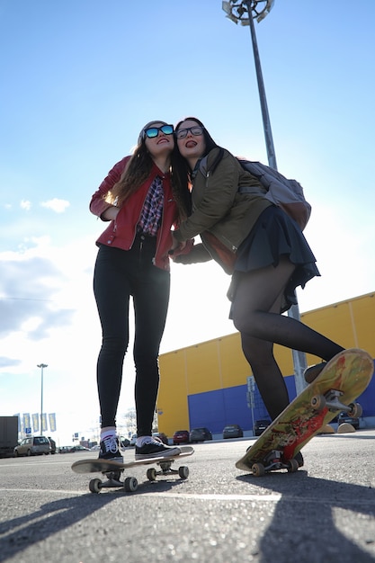 Una giovane ragazza hipster sta cavalcando uno skateboard. Amiche ragazze per una passeggiata in città con uno skateboard. Sport primaverili in strada con lo skateboard.