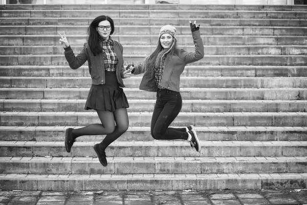 Una giovane ragazza hipster sta cavalcando uno skateboard. Amiche ragazze per una passeggiata in città con uno skateboard. Sport primaverili in strada con lo skateboard.