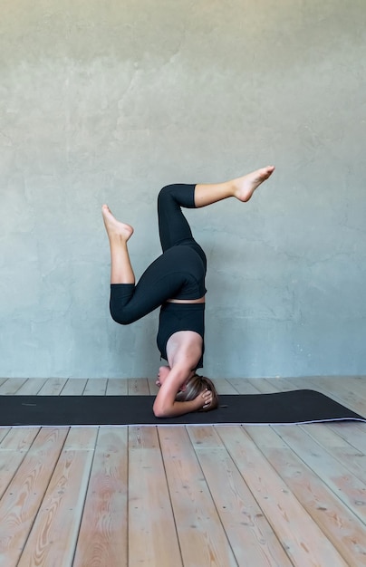 Una giovane ragazza in abbigliamento sportivo fa yoga fitness a casa sport a casa stretching