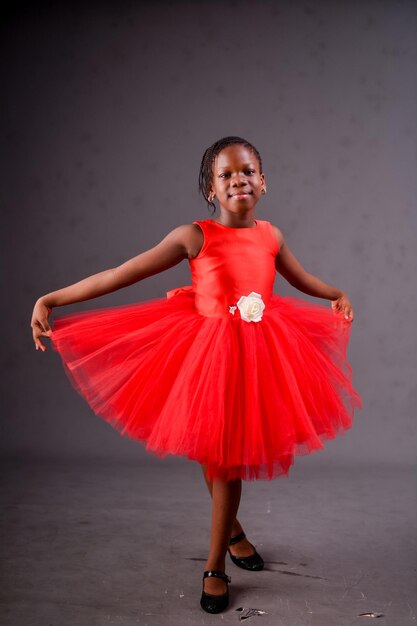 Una giovane ragazza in tutù rosso balla in uno studio.