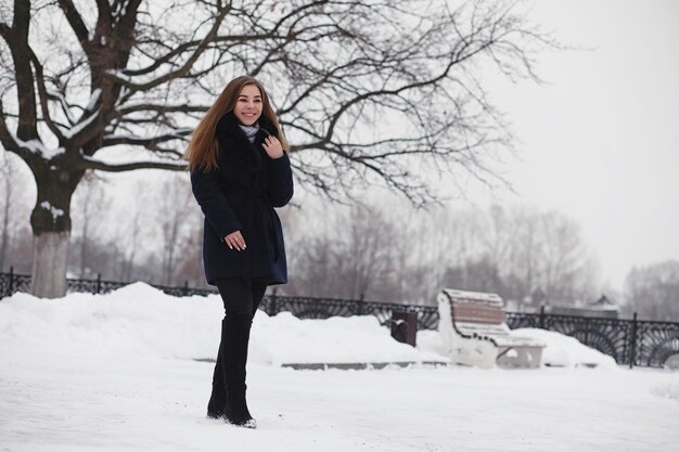 Una giovane ragazza in un parco invernale durante una passeggiata. Vacanze di Natale nella foresta invernale. La ragazza gode dell'inverno nel parco.