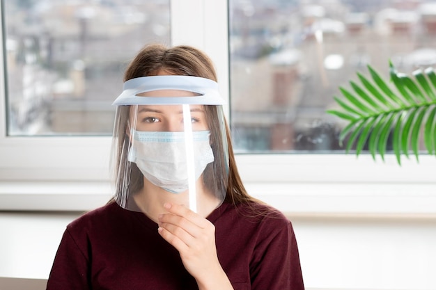 Una giovane ragazza indossa una maschera medica protettiva in plastica contro il coronavirus covid19