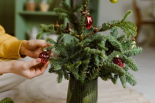 Una giovane ragazza raccoglie decorazioni natalizie dai rami di abete in cucina il concetto di Natale