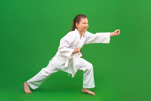 Una giovane ragazza si allena nel karate isolata su uno sfondo verde