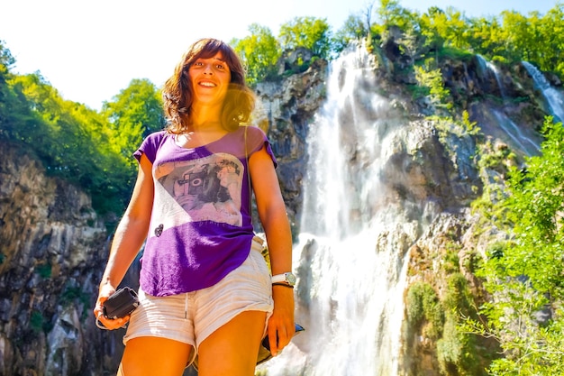 Una giovane ragazza sotto una cascata nel Parco Naturale di Plitvice in Croazia