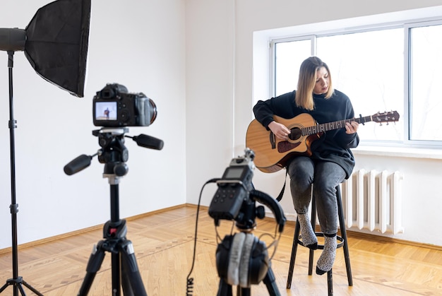 Una giovane ragazza suona la chitarra registrando video e suoni