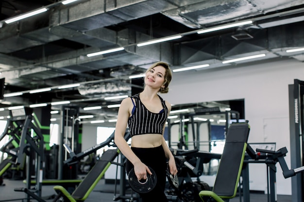 Una giovane sportiva caucasica si è impegnata in palestra, facendo l'esercizio di sporgersi in avanti con un pancake per il bar.