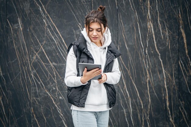 Una giovane studentessa sta con una tavoletta digitale nelle sue mani fuori