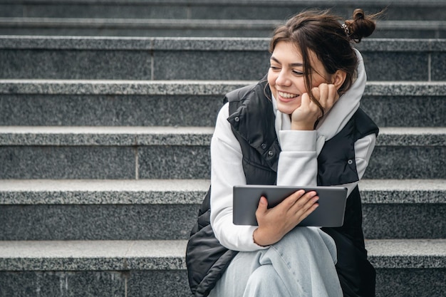 Una giovane studentessa sta con una tavoletta digitale nelle sue mani fuori