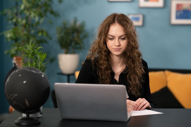 Una giovane studentessa sta studiando a distanza da casa sua femmina usa il laptop per navigare sui siti web