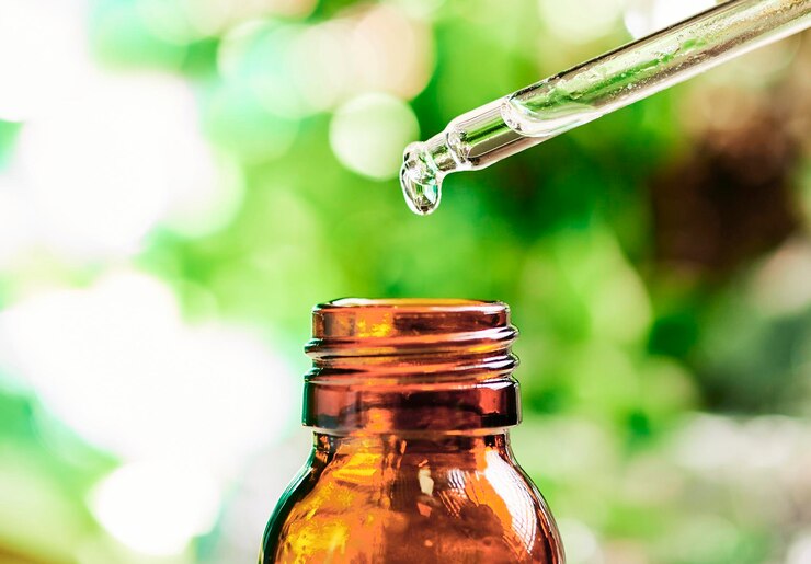 Una goccia di olio essenziale che cade da un contagocce in una bottiglia pronta per essere massaggiata con il concetto di aromaterapia