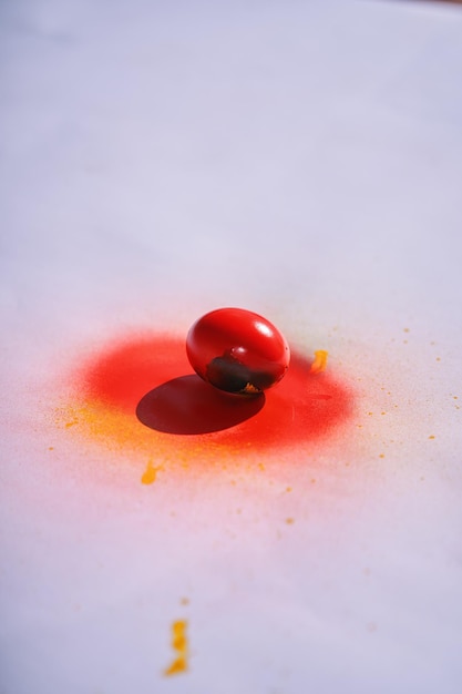 Una goccia rossa di sangue si trova su una superficie bianca con una goccia rossa al centro.