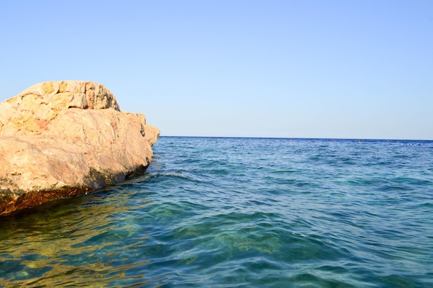 Una grande bella roccia di sabbia gialla un blocco di pietra immerso nell'acqua blu del mare di acqua salata