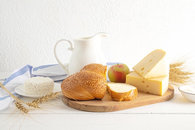 Una grande brocca di ricotta di latte pane tritato su un tagliere vista frontale prodotti lattiero-caseari tradizionali per la vacanza di Shavuot