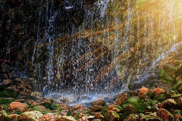 Una grande cascata in una grotta sotto i raggi del sole