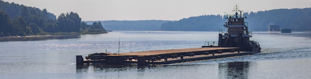 Una grande chiatta da carico trasporta merci via fiume al porto principale per essere caricate su grandi navi per l'esportazione. Trasporto merci via acqua