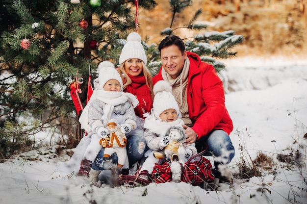 Una grande famiglia con bambini all'albero di Natale per strada Bambini felici con doni.