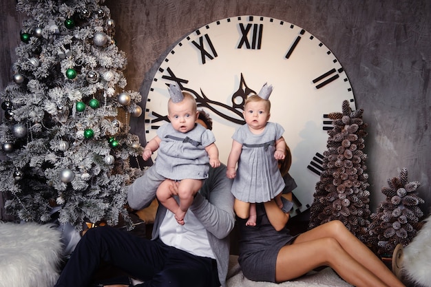 Una grande famiglia felice con bambini gemelli nell'interno della casa di Capodanno sullo sfondo di un grande orologio