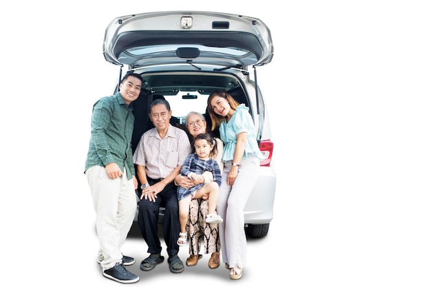 Una grande famiglia sorridente seduta sul bagagliaio dell'auto.