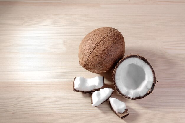 Una grande noce di cocco fresca e pezzi di cocco su uno sfondo di legno naturale. vista dall'alto