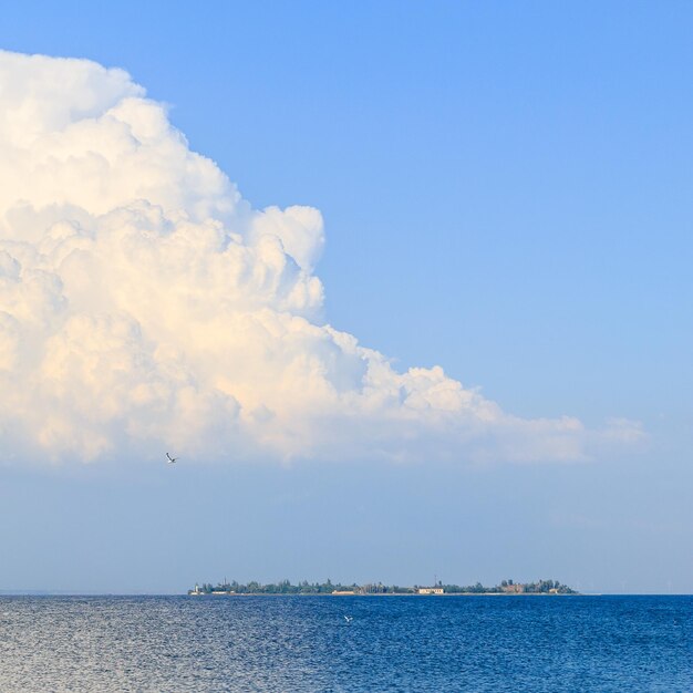 Una grande nuvola bianca sul mare un gabbiano nel cielo e un'isola