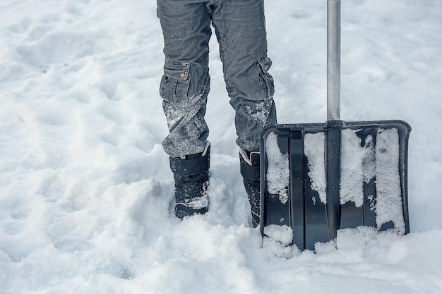 Una grande pala da neve accanto a un uomo con stivali invernali neri.