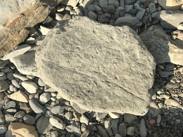 Una grande pietra giace su un ciottolo di mare sul pezzo di roccia della spiaggia