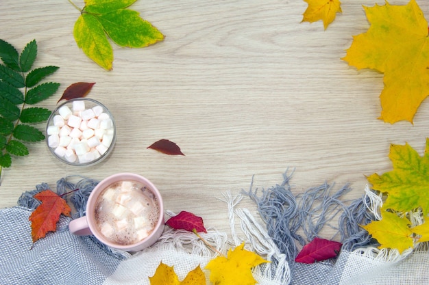 Una grande tazza di cioccolata calda con marshmallow e una calda coperta sullo sfondo di un vecchio legno