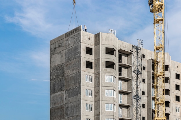 Una gru a torre assembla pannelli di grondaia durante la costruzione di una casa a pannelli. Costruzione di alloggi moderni. Ingegneria Industriale. Costruzione di abitazioni ipotecarie.