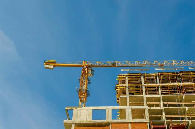 Una gru a torre sul cantiere di una casa contro il cielo.